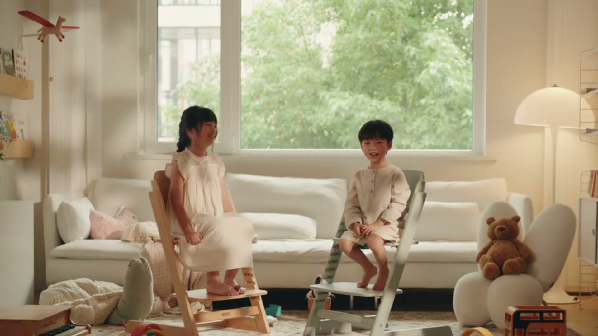 两个孩子坐在成长椅上的家庭生活画面 / Two children seated on growing chairs in a family living space